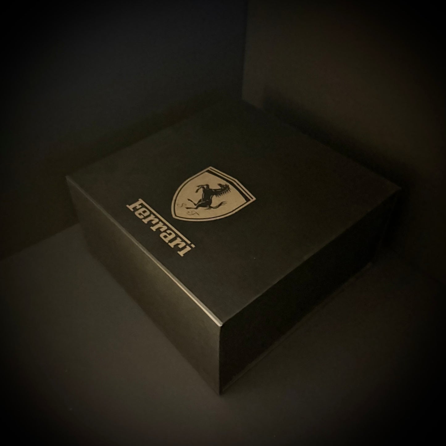 Ferrari logo on a dark box against a dark background