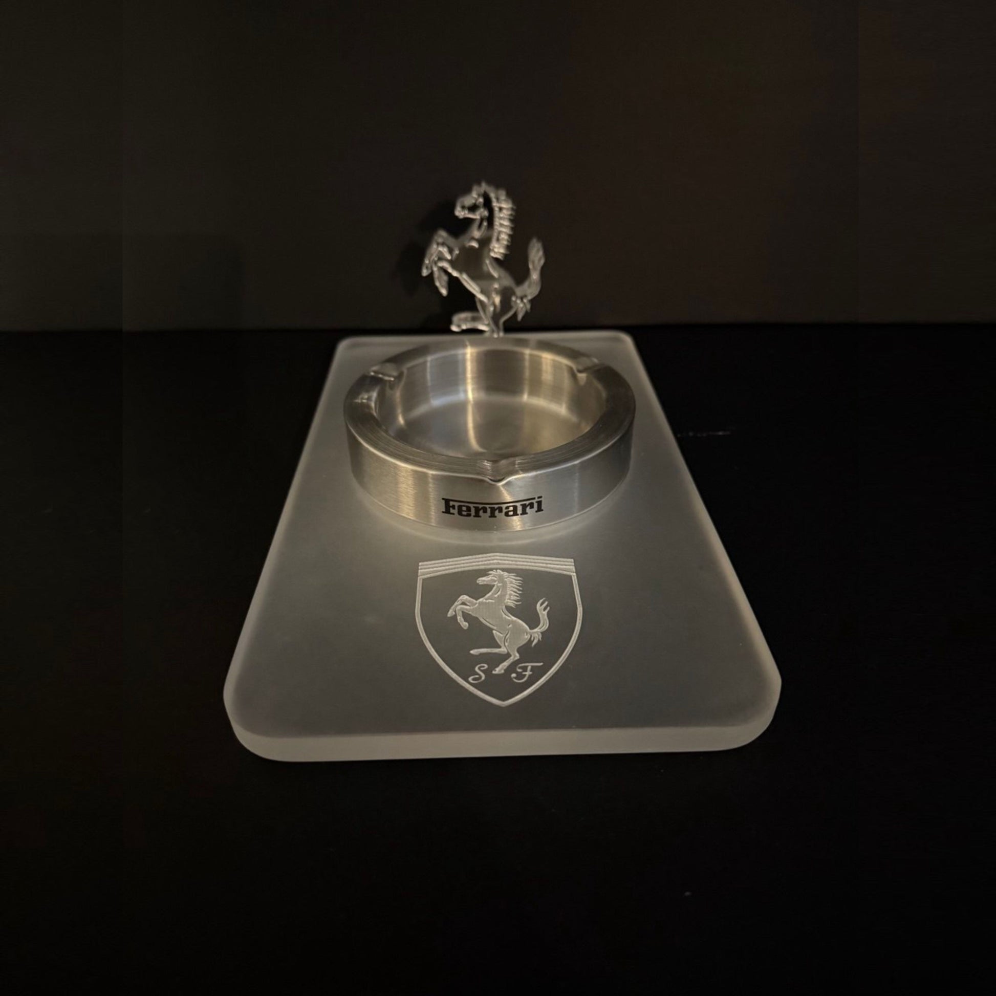 A clear acrylic ashtray with an engraved Ferrari shield and a 3D prancing horse figure mounted on a frosted acrylic base.