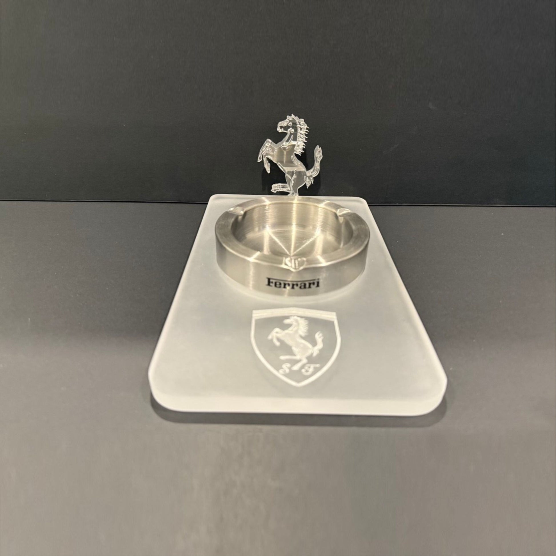 Three-quarter view of an acrylic Ferrari ashtray featuring a frosted base and a detailed clear 3D prancing horse figure.
