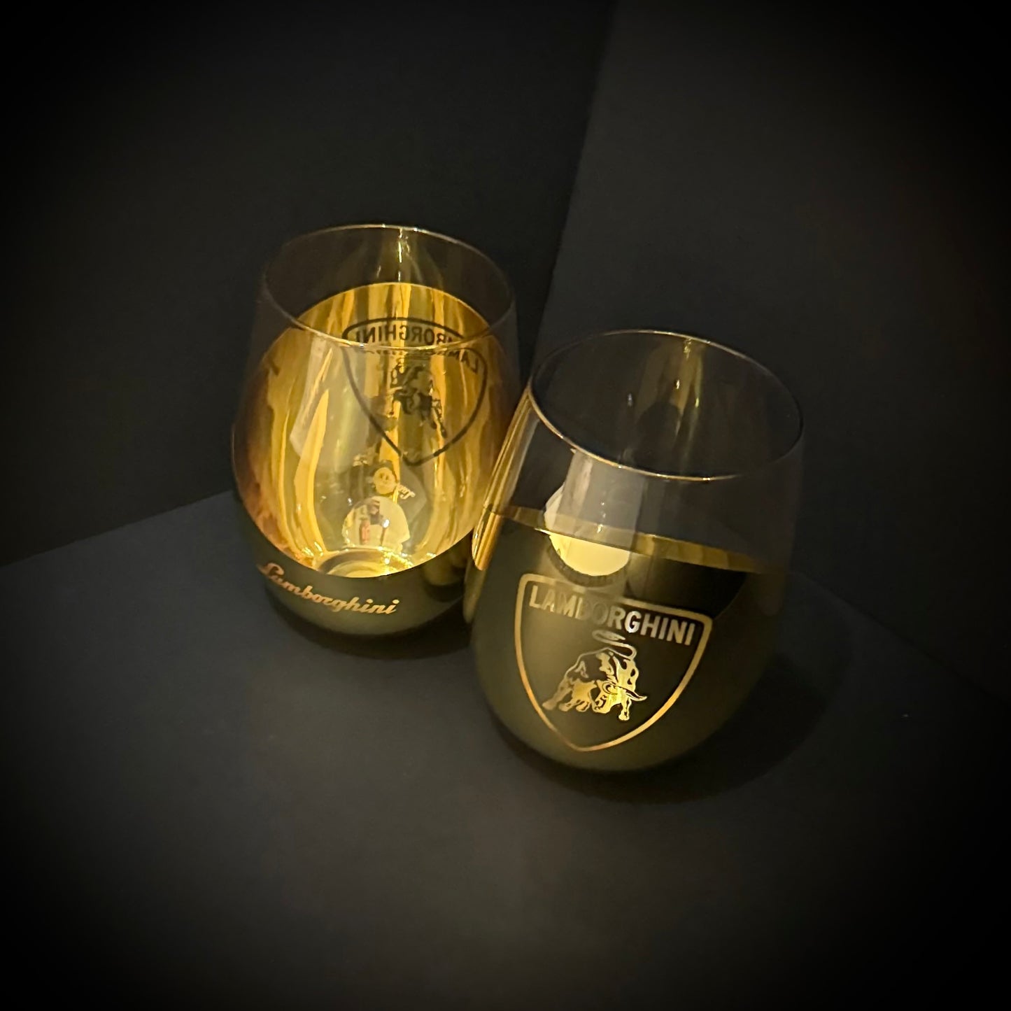 Two gold Lamborghini-branded glasses on a dark background
