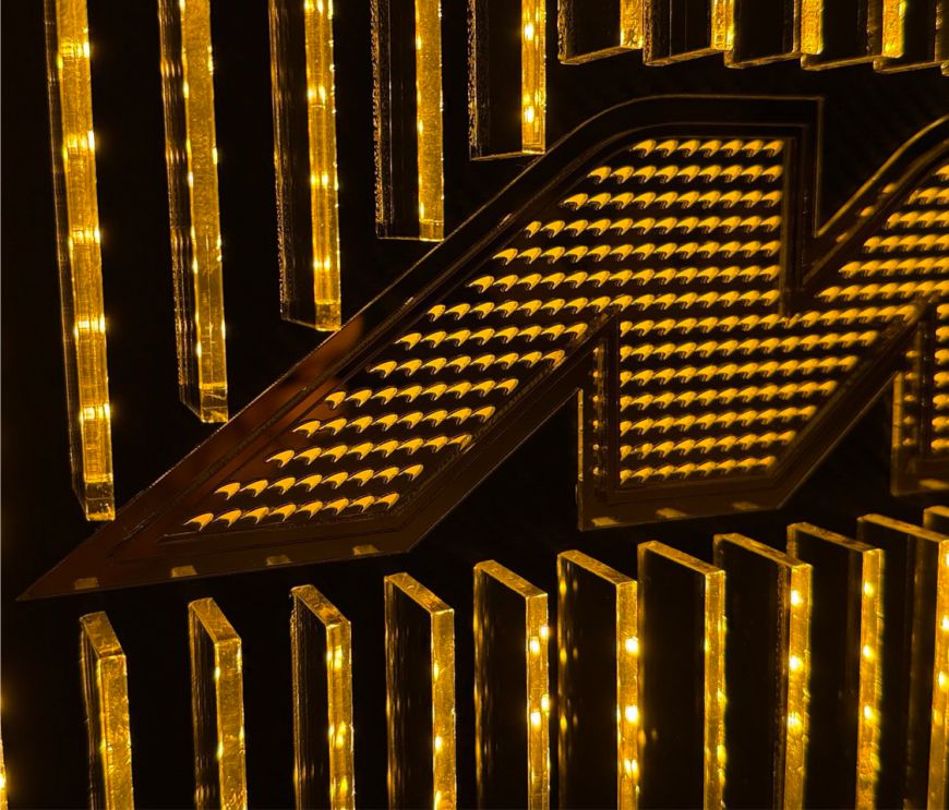 Close perspective of a McLaren-inspired layered acrylic sign with micro-logo detailing throughout, carbon-fiber paneling, and orange LED glow.
