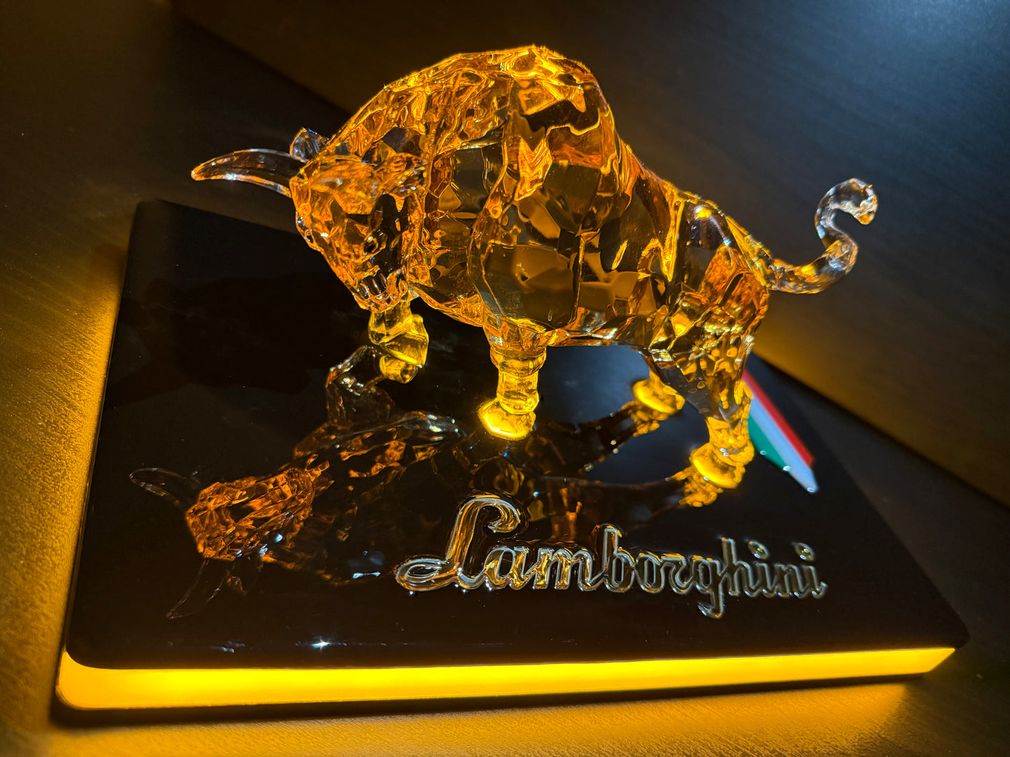 Golden illuminated bull artwork placed on an acrylic base with ‘Lamborghini’ engraving visible.