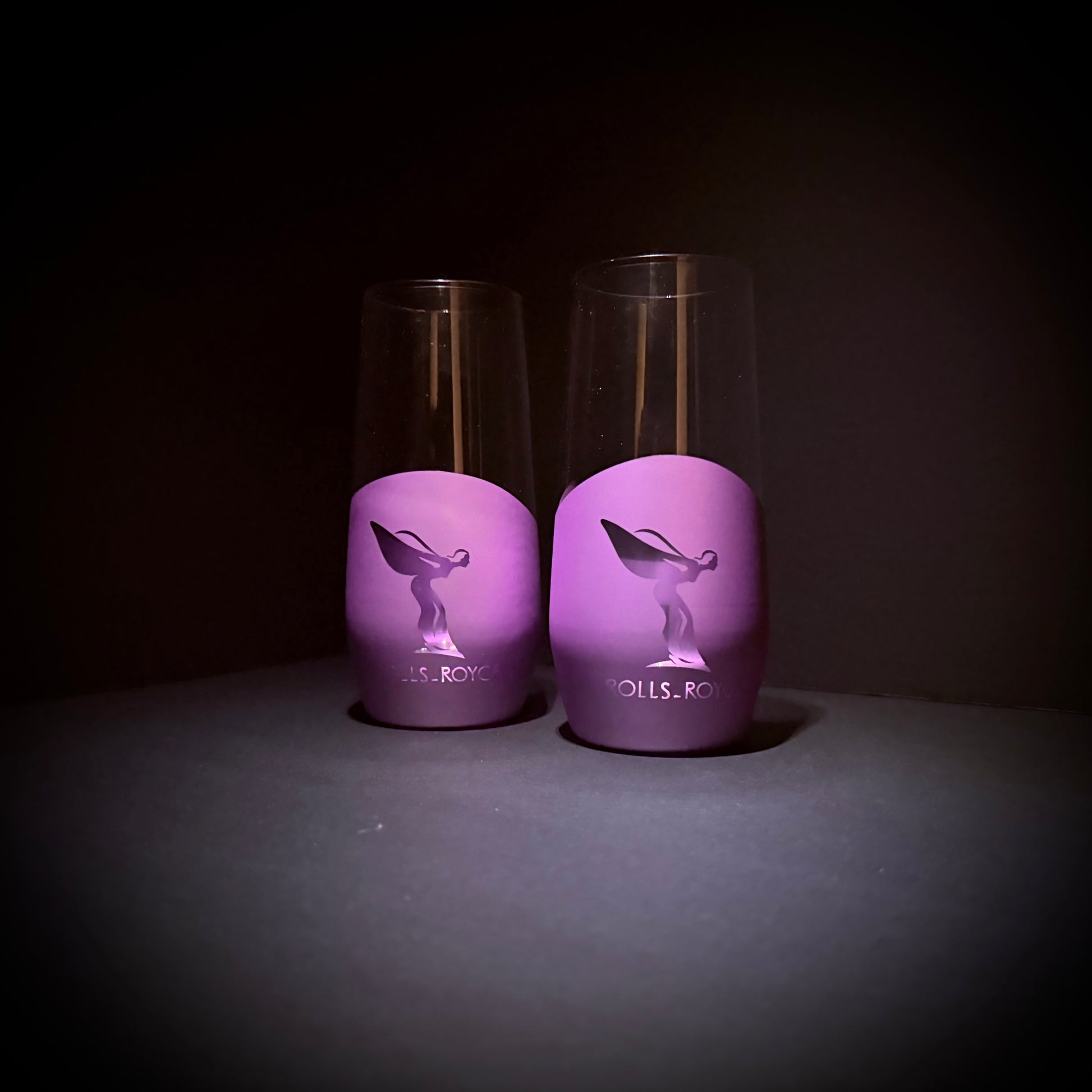 Two handcrafted purple glasses featuring RR-inspired engraving, lit with soft purple reflections.